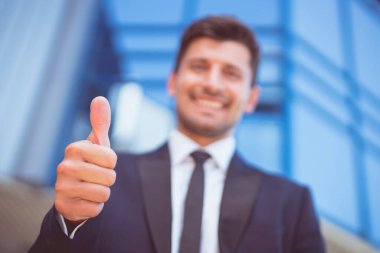 İş adamı modern binanın arka planında başparmak kaldırdı