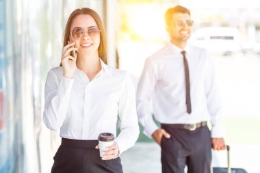 İş kadını, adamın yanında bir fincan kahve ve telefon tutuyor.