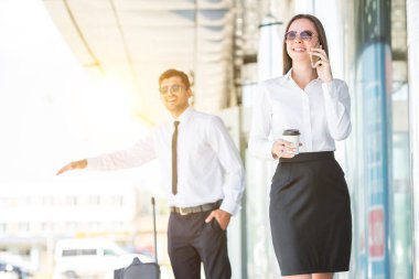 Mutlu kadın, erkeğin arka planında bir fincan kahve ve telefon tutuyor.