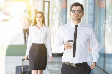 Yakışıklı işadamı bavullu kadının yanında duruyor.