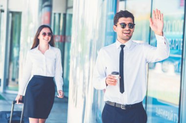 Güneş gözlüklü mutlu işadamı, kadının yanında el kol hareketi yapar.