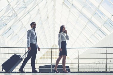 Mutlu iş adamı ve kadın bir bavulla yürür.