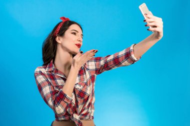 Güzel kadın mavi arka planda selfie çekiyor.