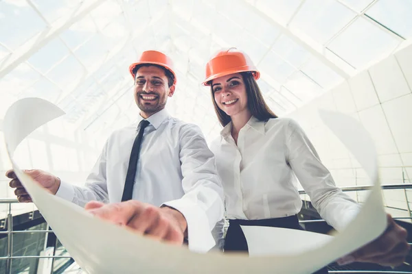 Two Builders Helmets Hold Project Plan Building — Stock Photo, Image