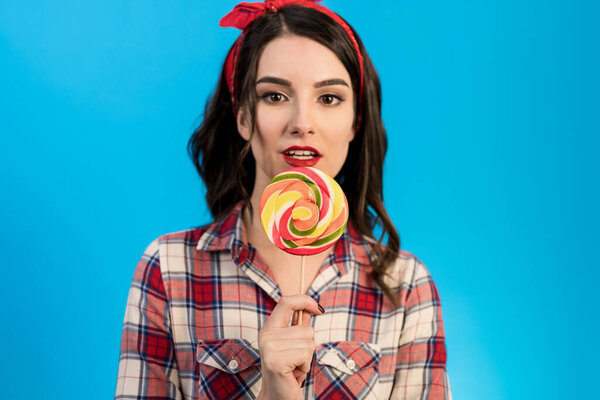 The portrait of the woman with a candy on the blue background