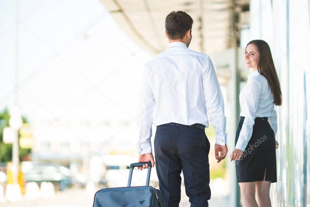 The business man and woman walk with a suitcase near building