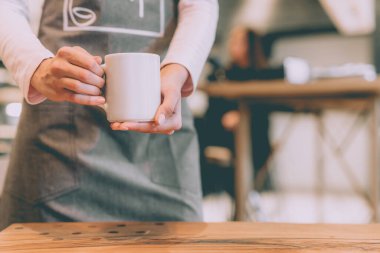 Garson kafede beyaz bir bardak tutuyor.