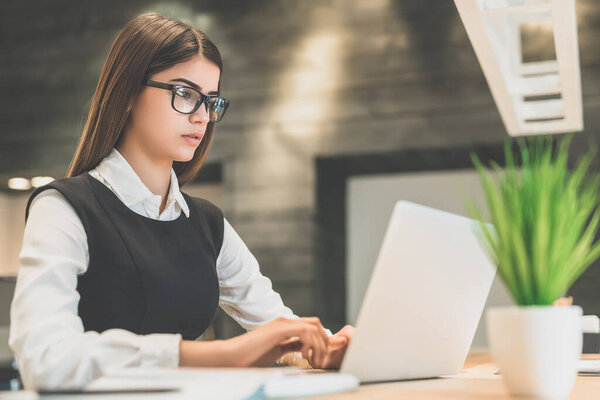 The beautiful woman with a laptop sitting at the desktop