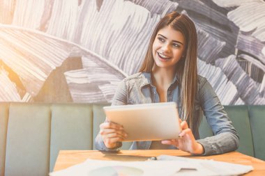 Kafede tablet tutan mutlu kadın.