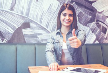 Kafedeki masada mutlu bir kadın baş parmağını kaldırdı.