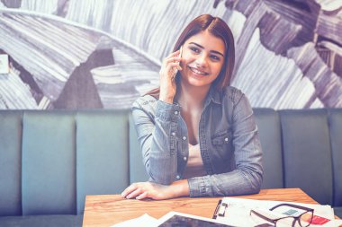Güzel kadın bir kafedeki masada telefon eder.