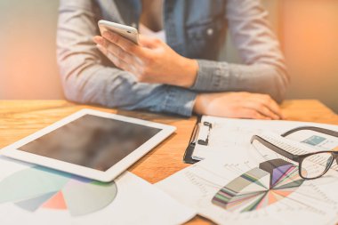 Masada telefon, kağıt ve dizüstü bilgisayarla çalışan kadın.