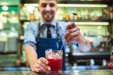 Mutlu barmen barda kırmızı kokteyl yapıyor.