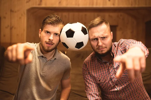 The two men with a ball gesture to the camera