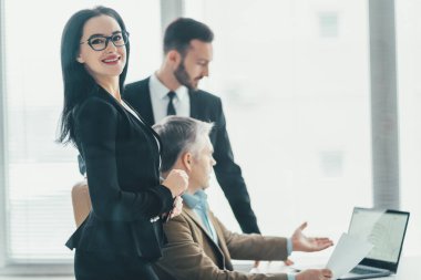 İş adamları dizüstü bilgisayarın yanında tartışıyor.