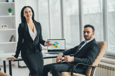 Ofis masasının yanında konuşan mutlu adam ve bir kadın.