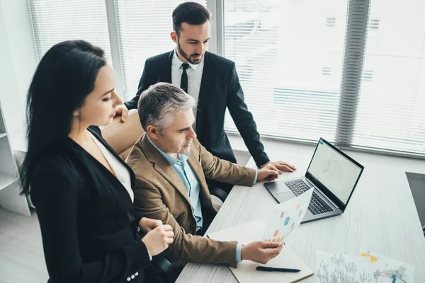 İş adamları dizüstü bilgisayarın yanında tartışıyor.