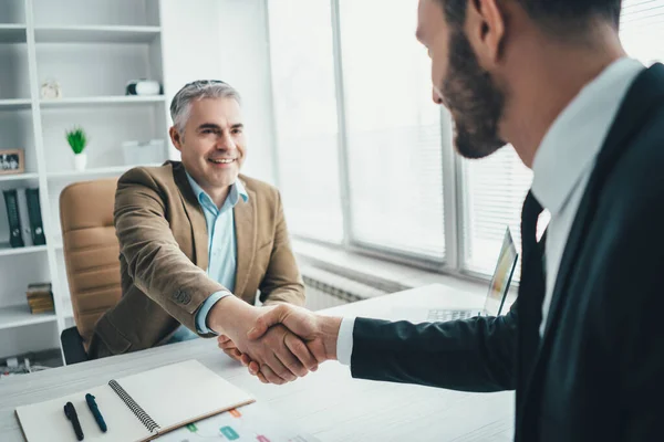 Ofisteki mutlu iş adamları el sıkışıyor.