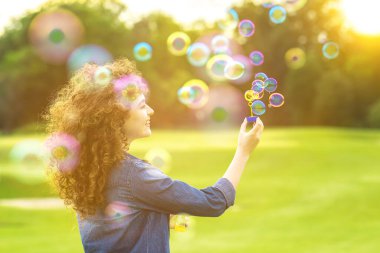 Yeşil parkta baloncuk çıkaran kadın.