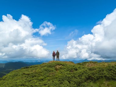 Dağda, bulutların üzerinde duran çift.