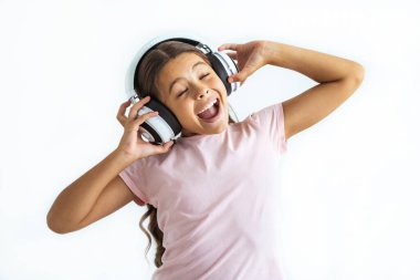 Beyaz duvar arkasında kulaklıkla müzik dinleyen mutlu kız.