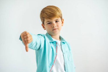 Küçük çocuk beyaz arka planda baş parmağıyla...