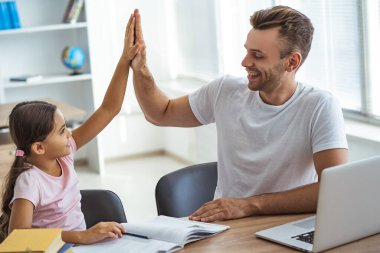 Mutlu baba ve kızı masada oturup el kol hareketi yapıyorlar.