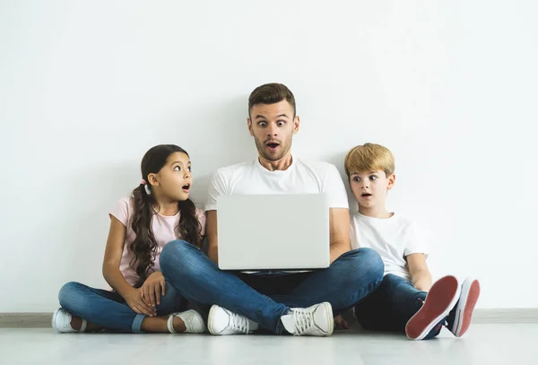 Padre Sorpreso Bambini Con Computer Portatile Seduto Sul Pavimento — Foto Stock