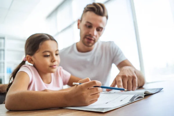 The man and a girl doing homework at the desk