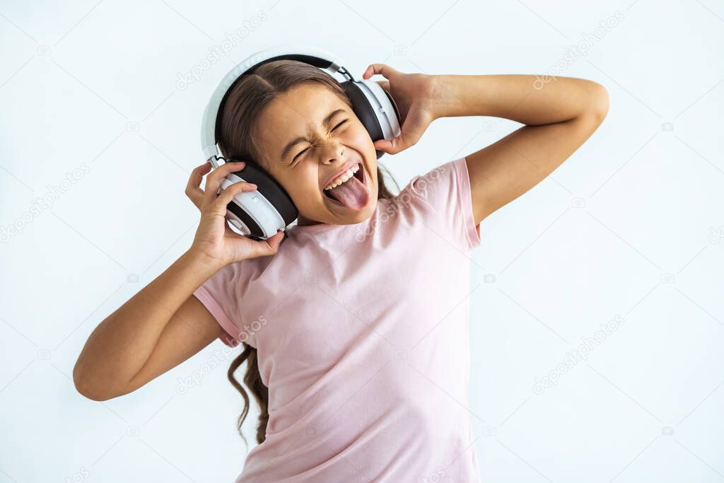 The emotional girl listening music in headphones on the white wall background