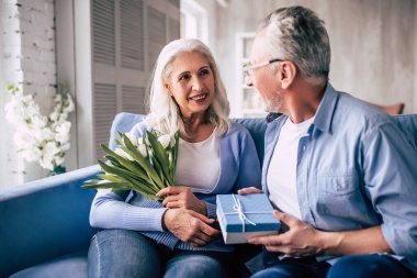 Yaşlı adam çiçekli bir kadına hediye veriyor.