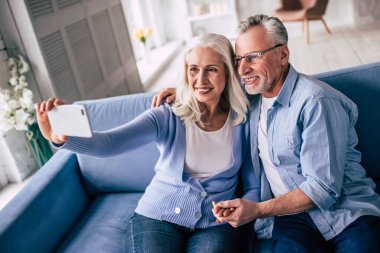 Mutlu yaşlı adam ve bir kadın selfie çekiyorlar.