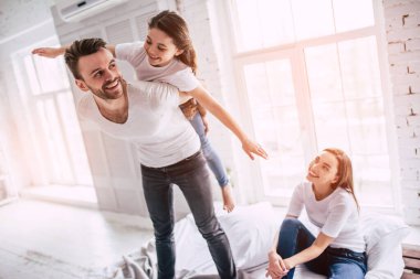 Anne babasıyla yatakta oynayan kız.