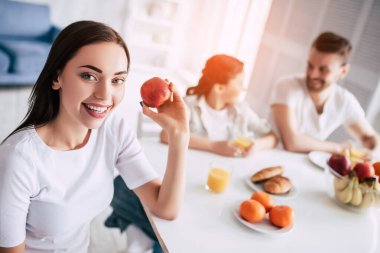 Ailenin yanında elma tutan mutlu kadın.