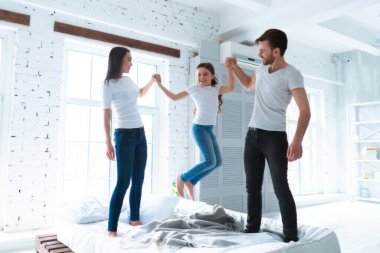 Anne babasıyla yatakta zıplayan tatlı kız.