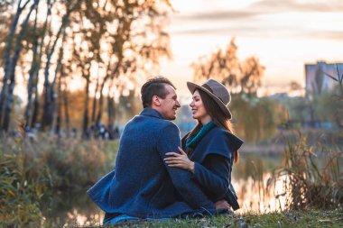 Göl kenarında oturan mutlu çift manzaralı arka planda