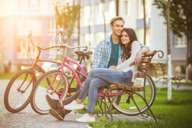 Bisikletli mutlu çift modern evin yanındaki bankta oturuyor.