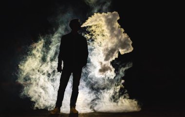 Karanlık arka planda sigara içen adam. Akşam vakti.