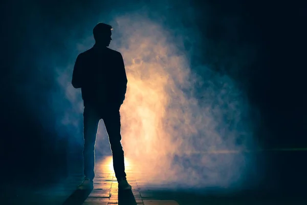 Sisin içinde duran adam. Akşam vakti.