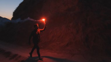 Elinde sopayla dağlarda yürüyen adam.