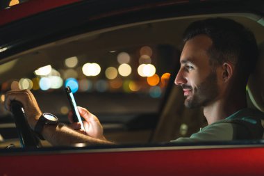 Arabada oturan akıllı telefonlu çekici adam.