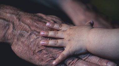 Küçük çocuk yaşlı büyükbabasıyla oynuyor.