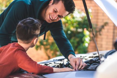 Baba oğul arabanın kaputunu tamir ediyor.