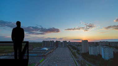 Büyük şehrin arka planında balkonda duran adam.