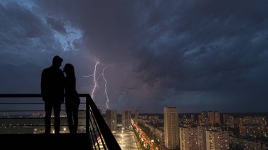 Yağmurlu arka planda balkonda duran romantik çift.