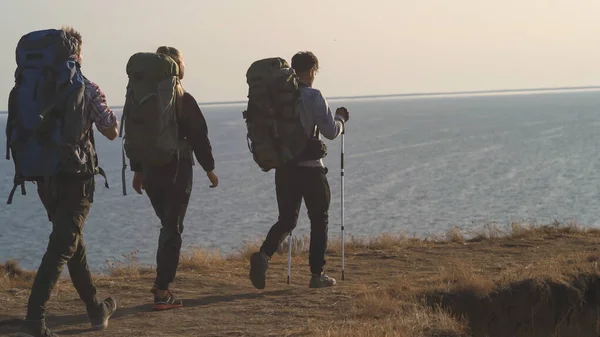 Tiga Pelancong Dengan Ransel Berjalan Latar Belakang Pemandangan Laut — Stok Foto