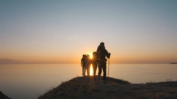 Neljä Turistia Kävelee Lähellä Merta Kauniilla Auringonlaskun Taustalla — kuvapankkivalokuva