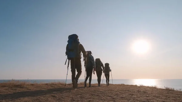 Keempat Pelancong Dengan Ransel Berjalan Latar Belakang Pemandangan Laut — Stok Foto
