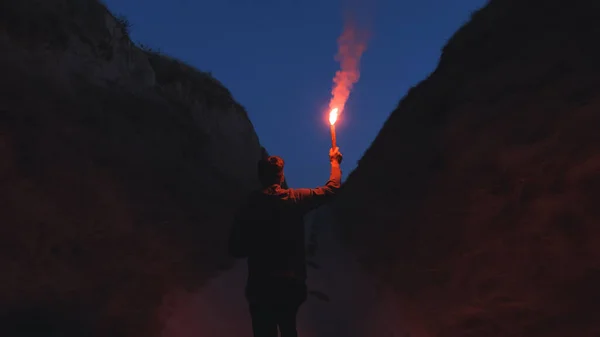 The man with a fire stick walking in the mountains