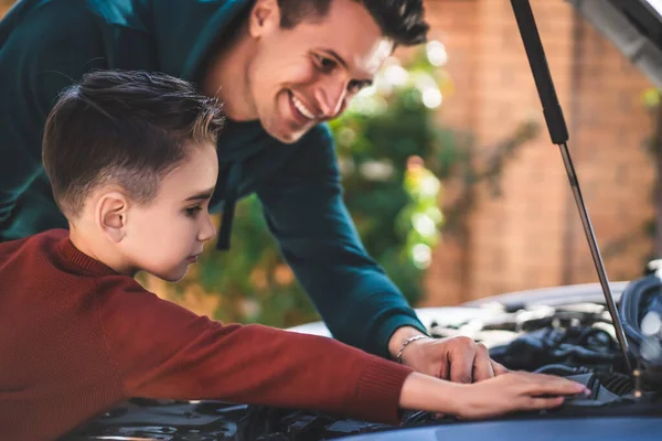 The father and son checking under the car hood